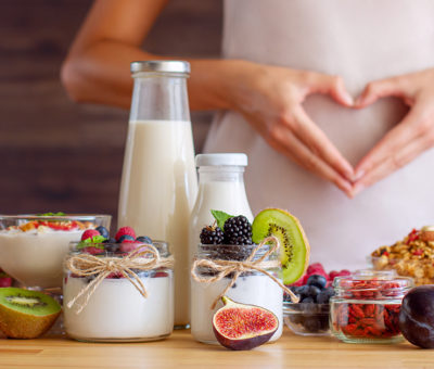 Eine Frau formt mit ihren Händen ein Herz auf ihrem Bauch.