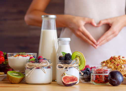 Eine Frau formt mit ihren Händen ein Herz auf ihrem Bauch.