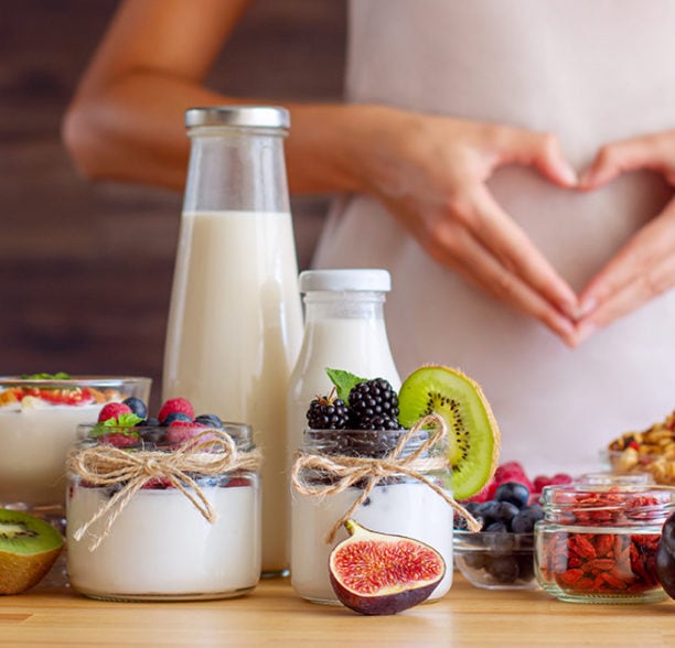 Eine Frau formt mit ihren Händen ein Herz auf ihrem Bauch.